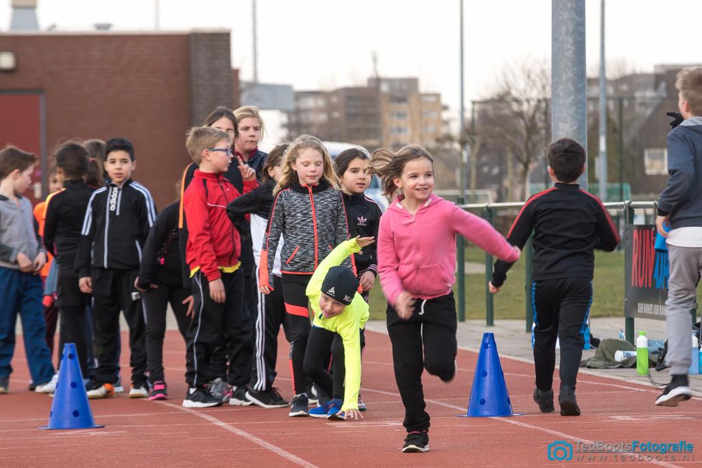 Kinderen die op een atletiekbaan rennen. 