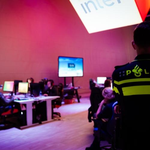 Een politieagent kijkt naar een computerscherm in een donkere ruimte.