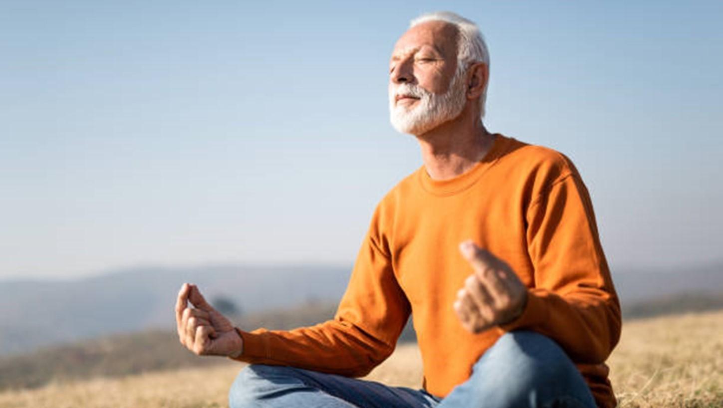 Oudere man die yoga oefeningen aan het doen is 