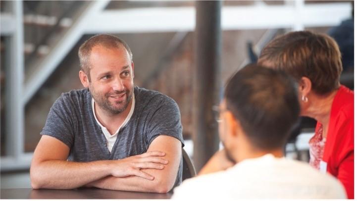 Drie mensen in gesprek aan een tafel 
