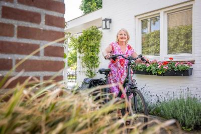 Afbeelding vrouws in tuin met fiets haar hand 