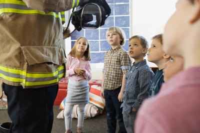 Kinderen die uitleg krijgen van een brandweerman